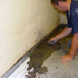 A basement waterproofer installing a perimeter drain system in Hicksville