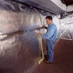 Installation of a radiant heat and vapor barrier on a basement wall in Smithtown