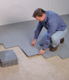 Contractors installing basement subfloor tiles and matting on a concrete basement floor in Bay Shore, Long Island